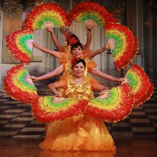 Female Chinese dancers in orange dresses and colourful fans